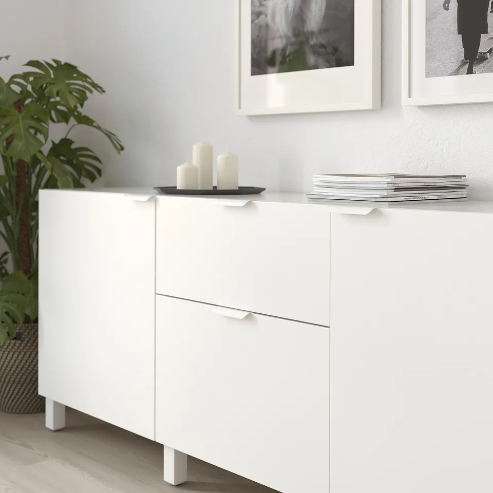 White cabinet with BILLSBRO handles, displaying candles and books, featuring modern design.