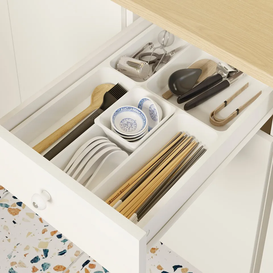 A well-organized kitchen drawer with sections for plates, bowls, chopsticks, spoons, and kitchen tools.