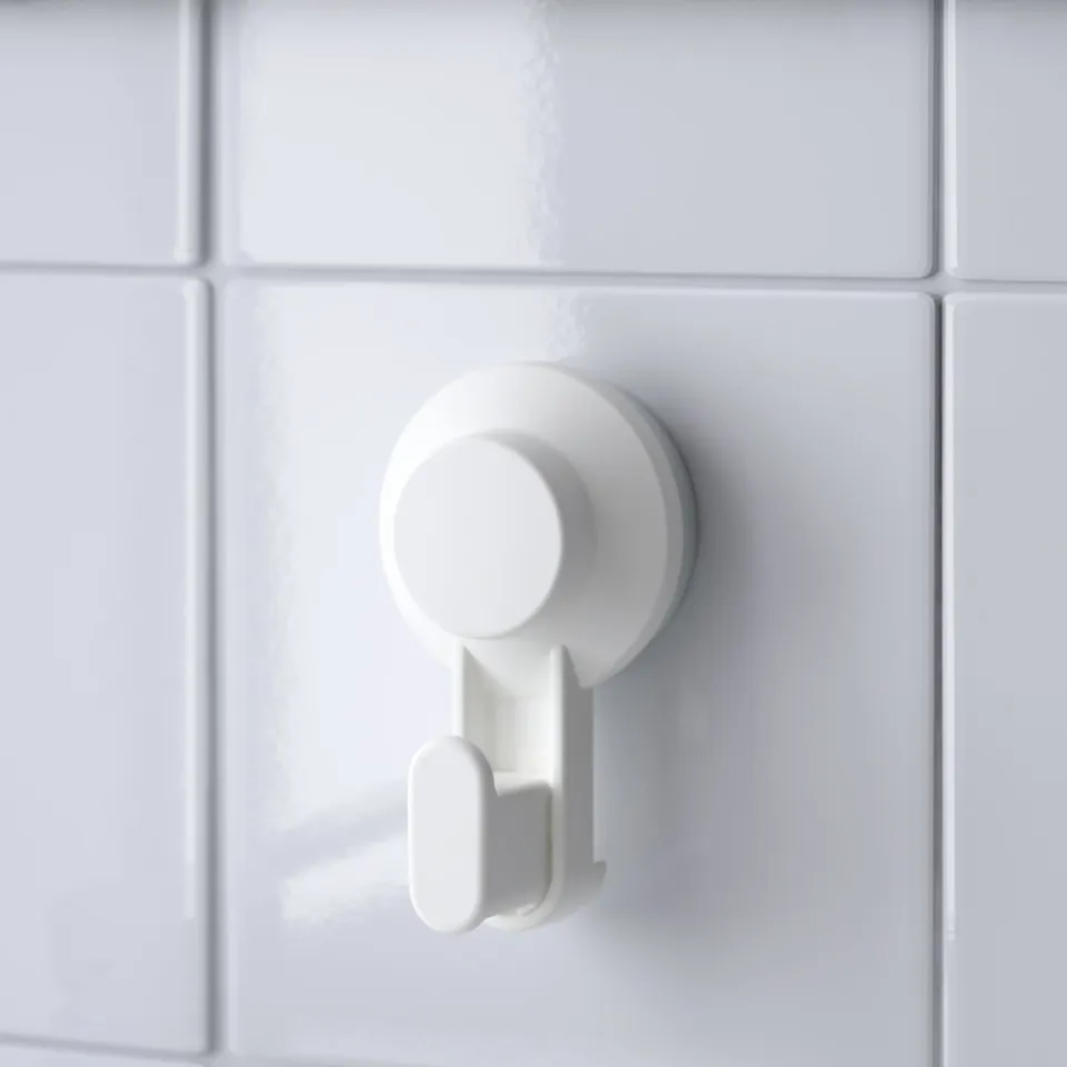 Single white suction cup hook on tiled wall. Secure, no-damage attachment for hanging items.