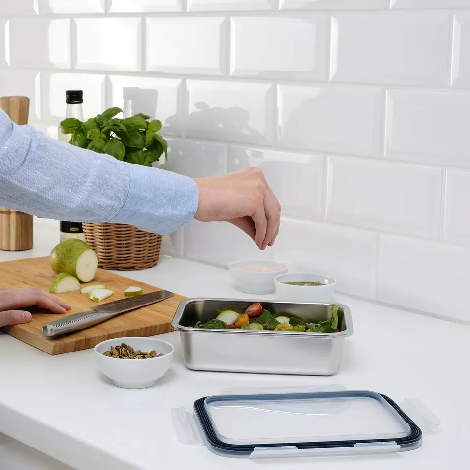 Preparing salad in stainless container with leakproof, clear lid.