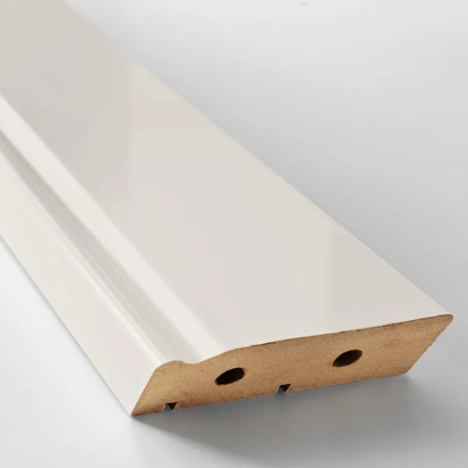 White kitchen plinth, made of fiberboard and plastic. Shows two holes on one end.