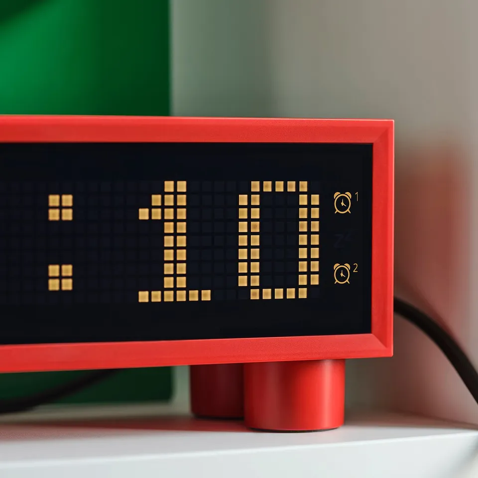 Modern, red digital clock on a white shelf, displaying time 11:11. Shows temperature and humidity, with sleek, pixelated display.
