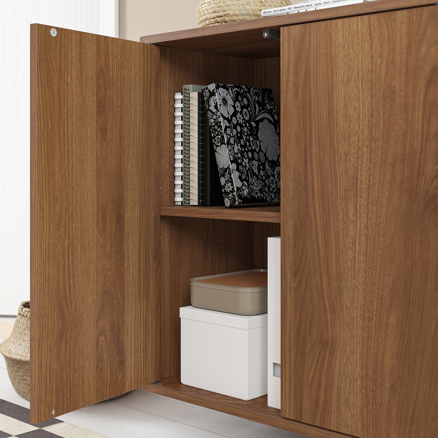 Wooden cabinet with open door, storing books and boxes.