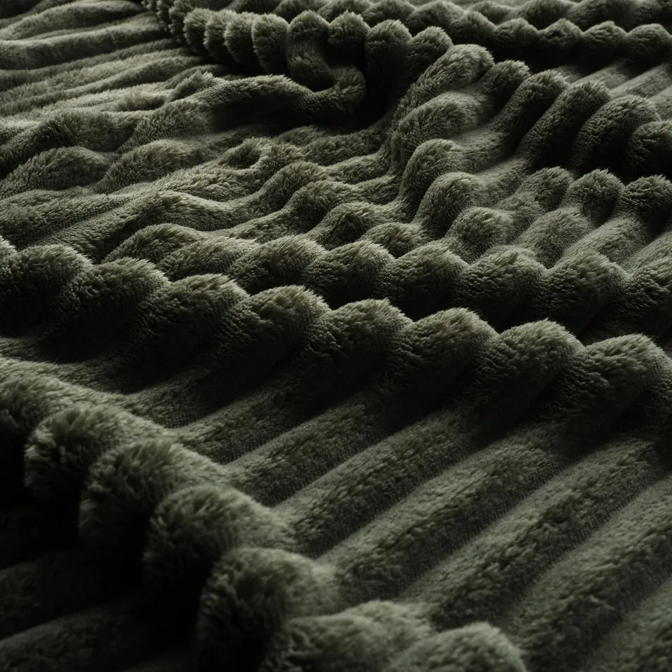 Dark green plush blanket, textured with wavy patterns, appears soft and inviting.
