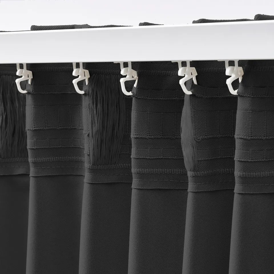 Curtain hooks suspending KORGMOTT dark grey block-out curtains, showing off their durable woven fabric and functional, coordinated design.