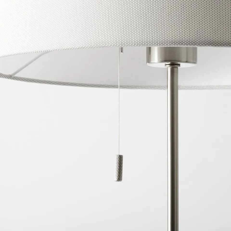 Modern floor lamp close-up: adjustable, sleek metal body, white shade, hanging switch.