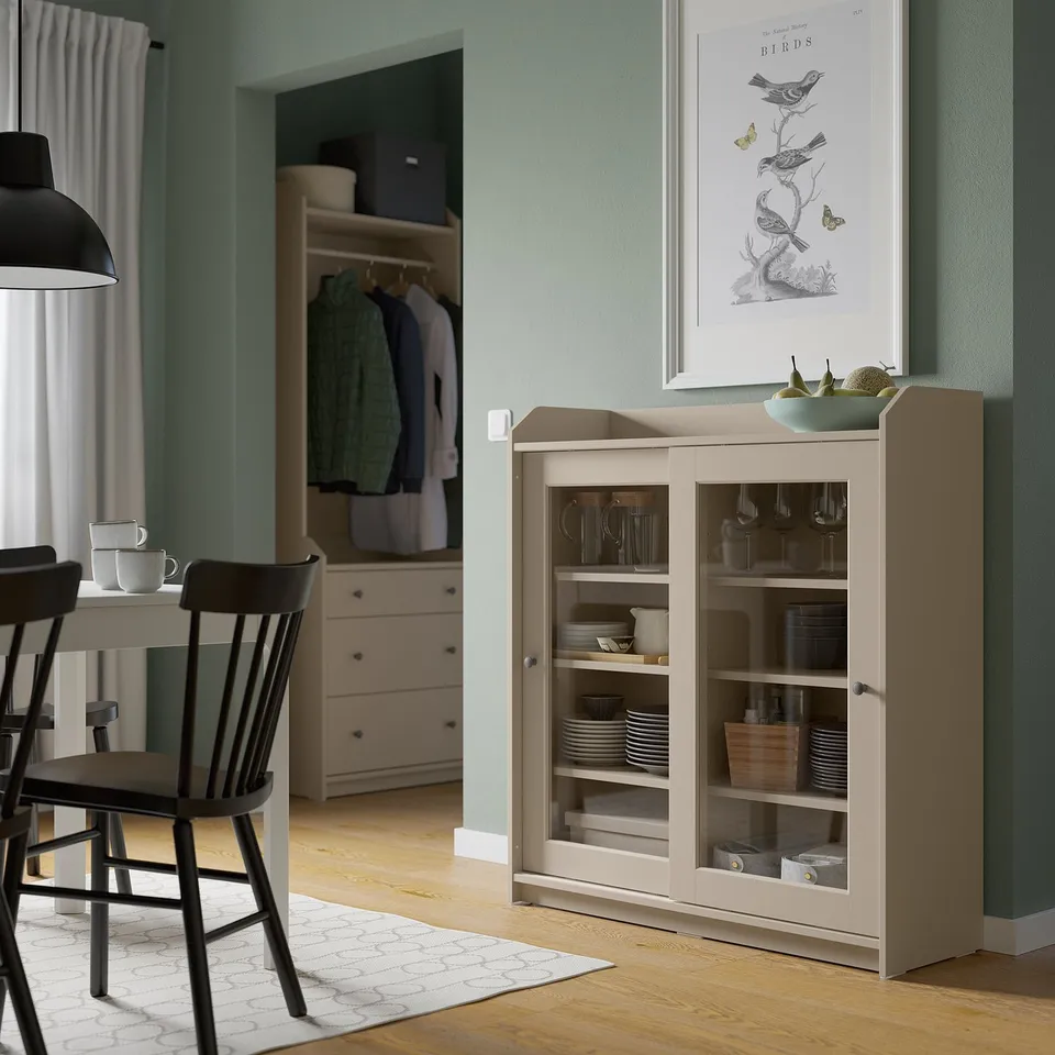 Modern dining with HAUGA cabinet, glass doors, black chairs, wood table, green walls, butterfly art, open closet.