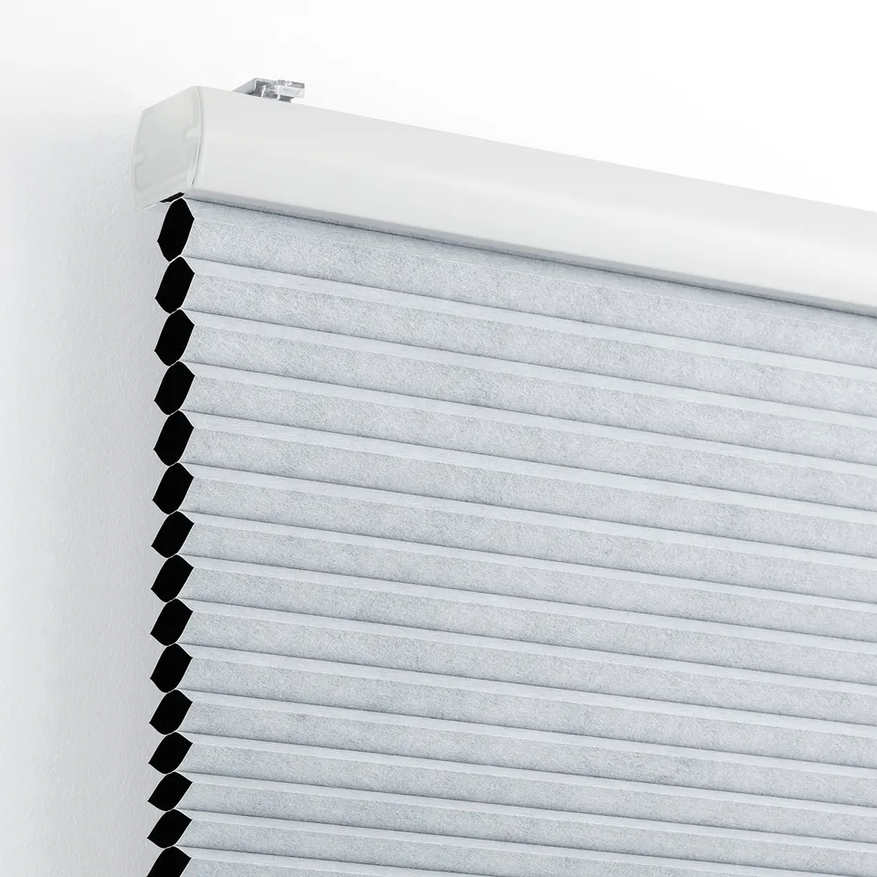 A white block-out blind with honeycomb structure, mounted on a wall, providing light control and insulation.