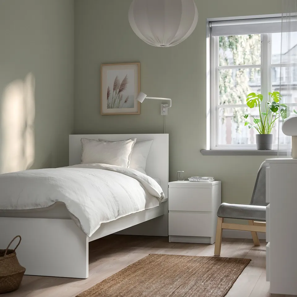 Modern bedroom with MALM bed in light colour, white bedding, green walls, and a simple design.