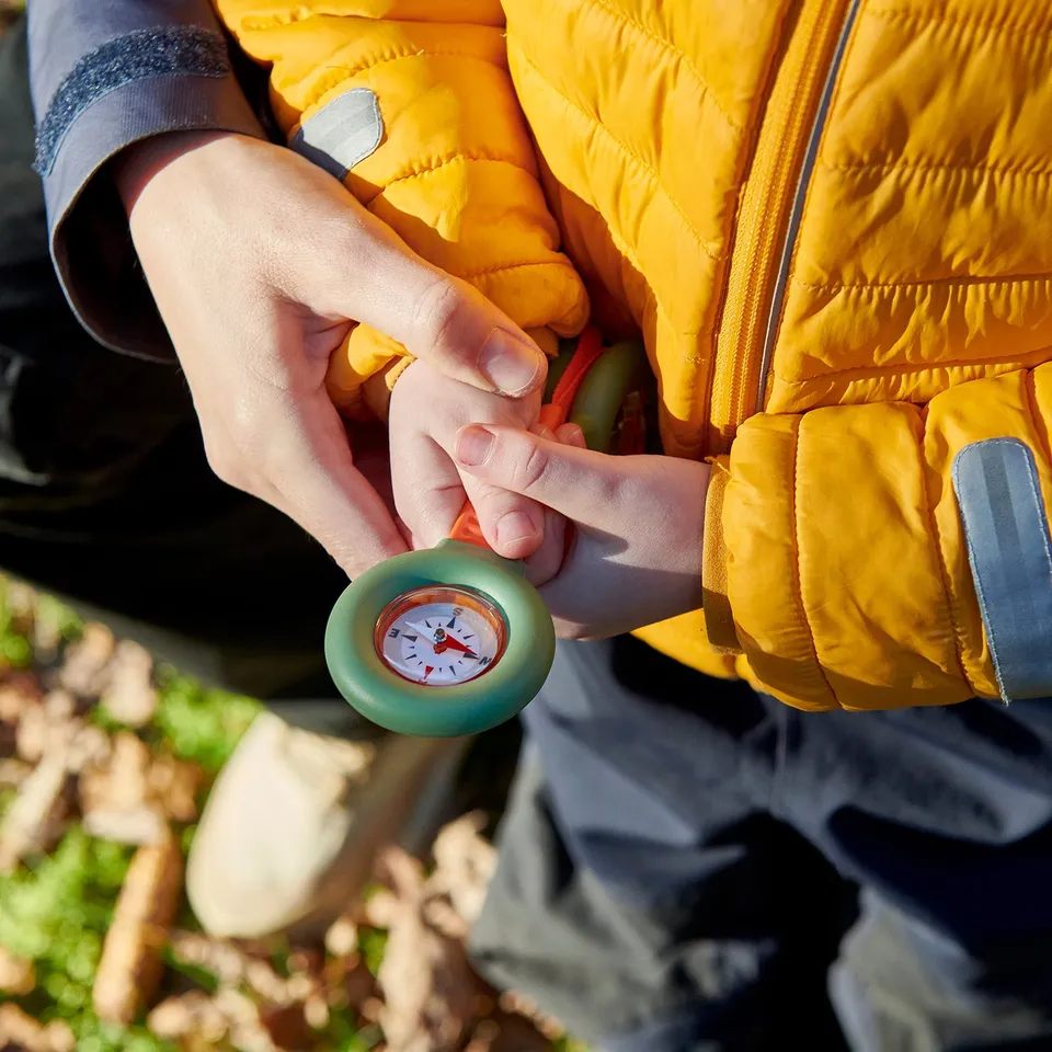 Child using compass toy with magnifying glass and prism.