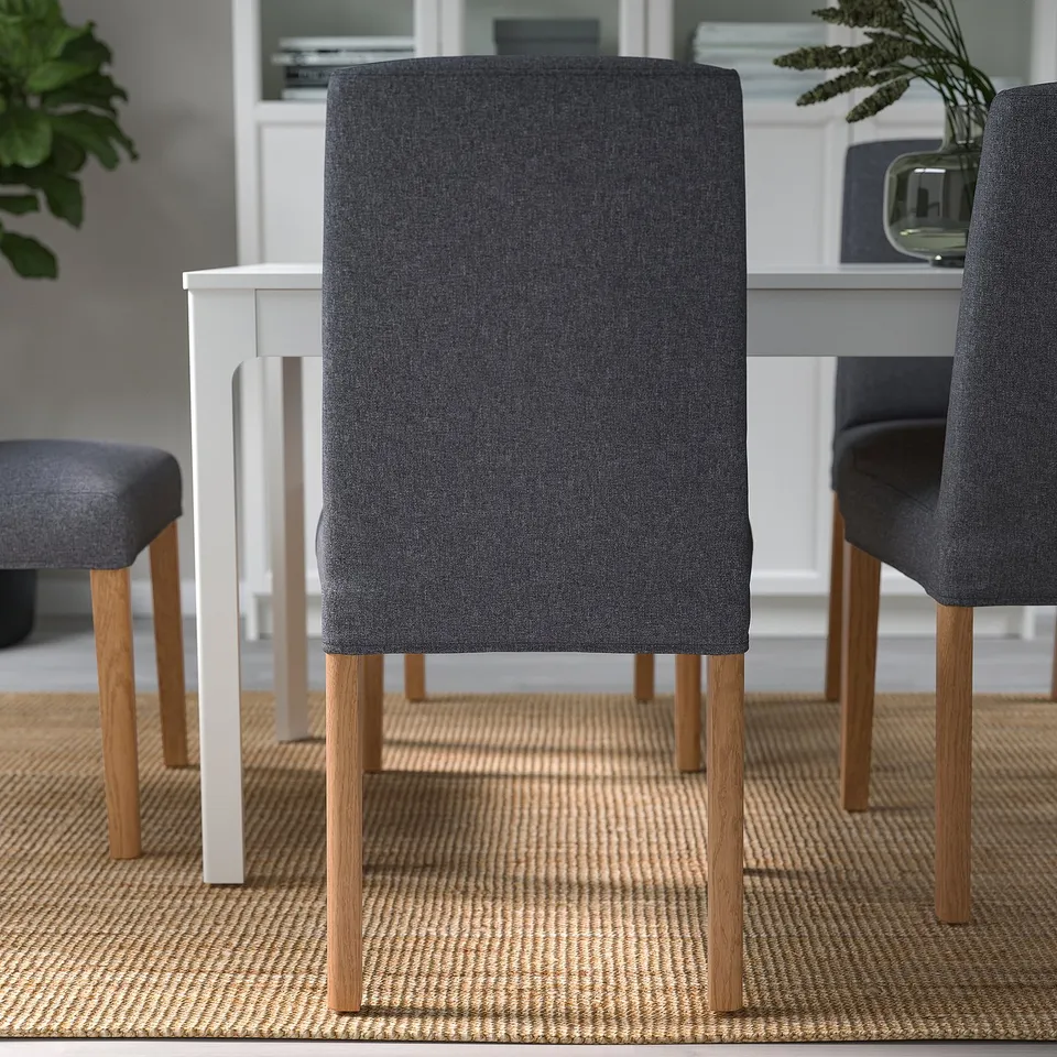 Modern dining setup with grey upholstered chairs around a white table on a woven rug.