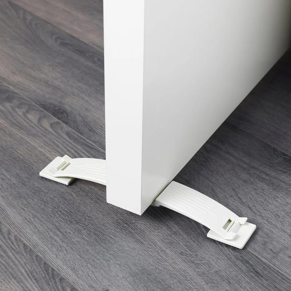 A white door stop securely attached to both sides of a door. It prevents the door from slamming shut, ensuring safety, especially for children.