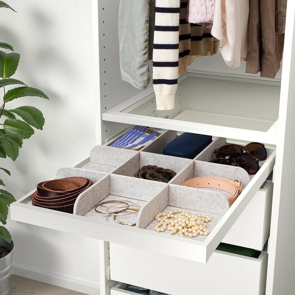 Organised drawer with felt compartments for belts, jewellery, and accessories in a white cabinet.
