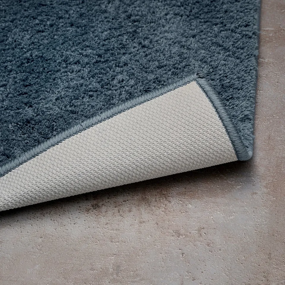 Grey bath mat with white backing, made from recycled polyester.