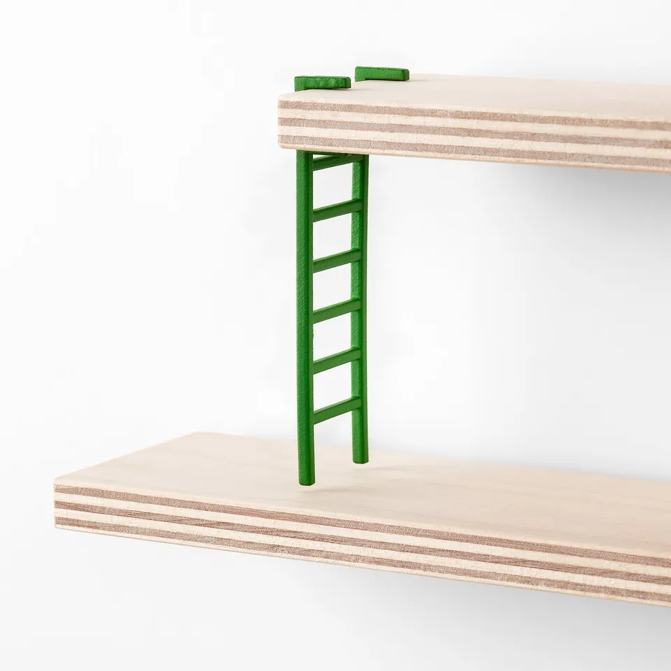 A mini wooden ladder with green plastic steps, resting on light wood panels.