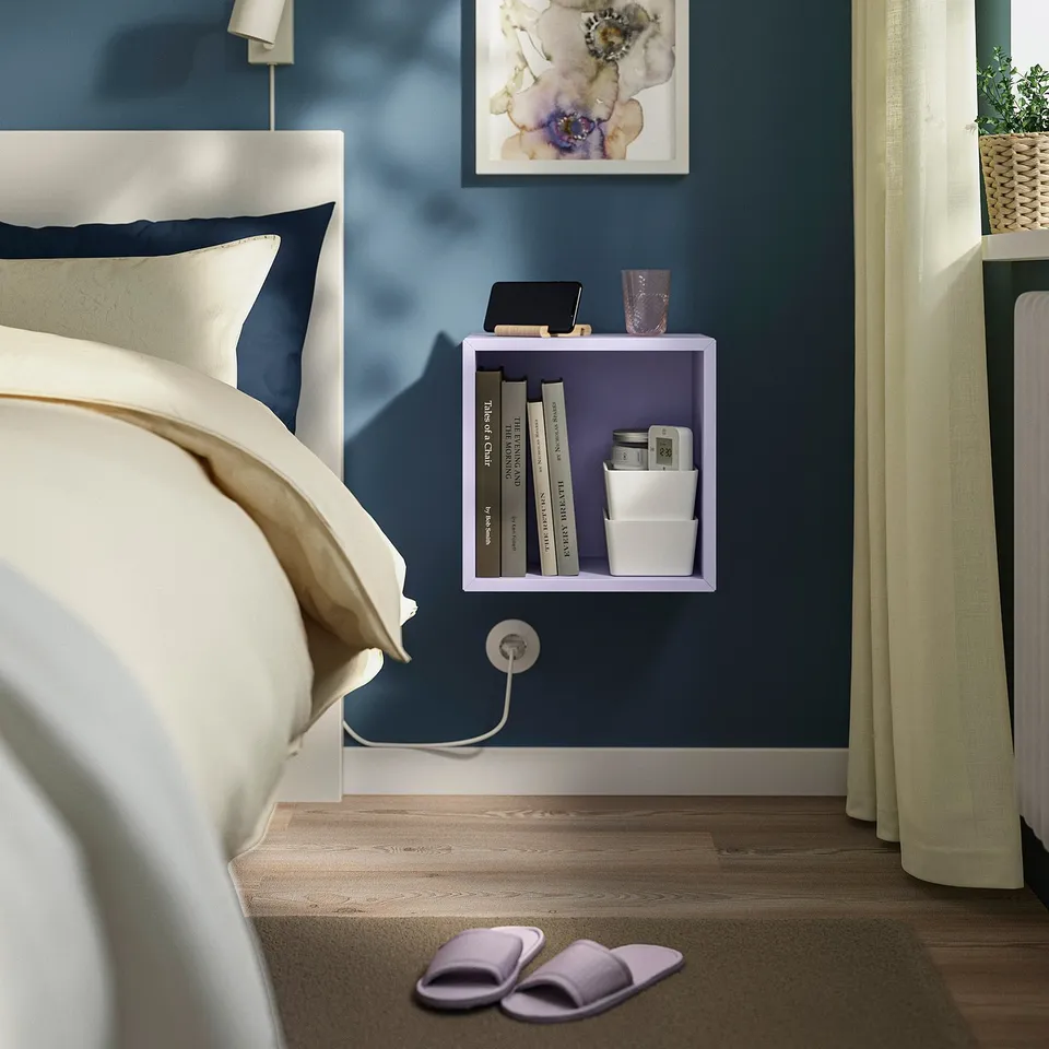 Blue bedroom with white bed, purple EKET shelf, slippers, curtain, plant.
