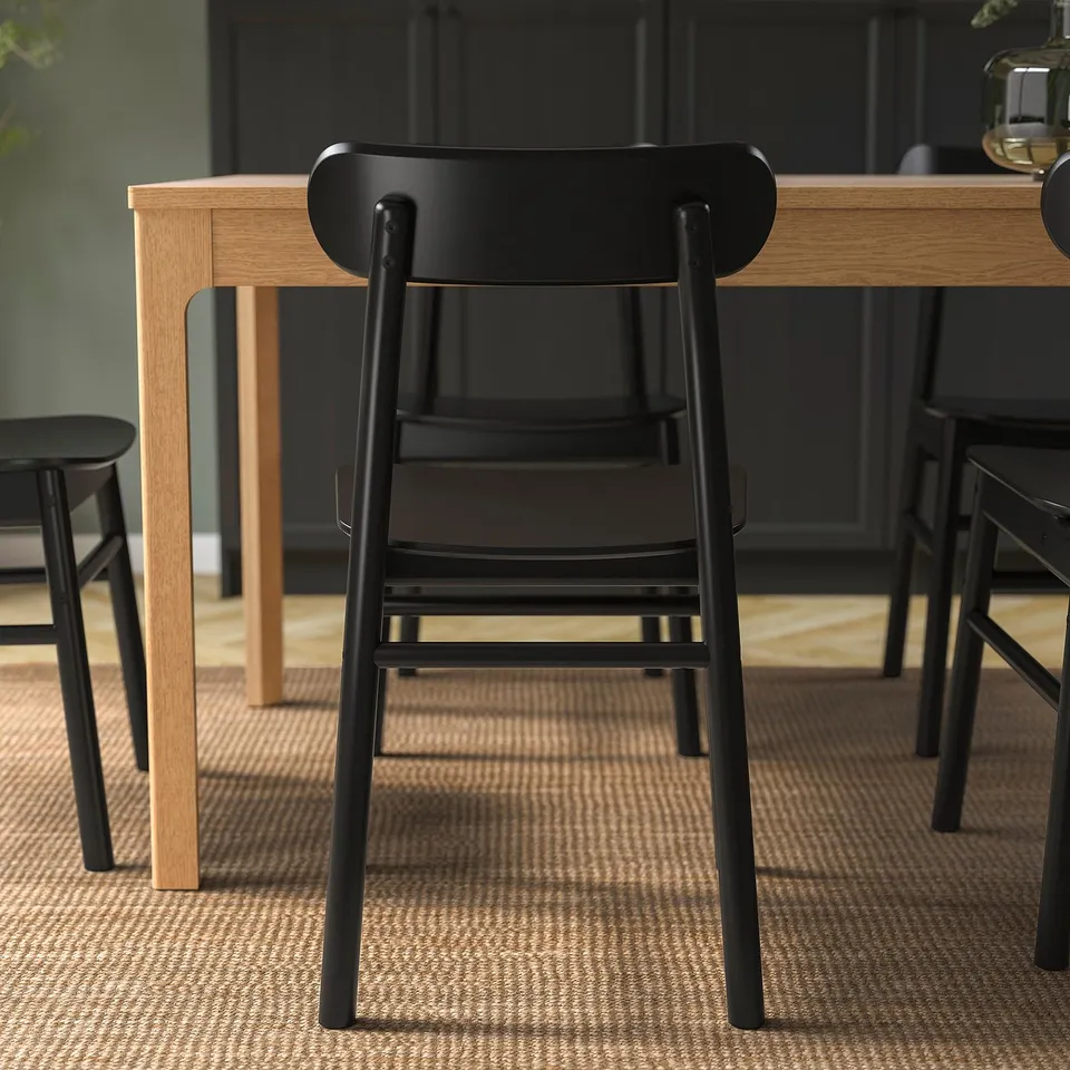 Black modern chair with wooden table. Simple, robust design with visible wood grain. Suitable for various spaces, durable for long use.
