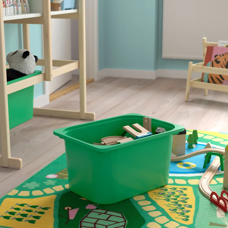Kids storage: green bin holds wooden blocks, next to toy train on colourful mat; shelf with stuffed panda.