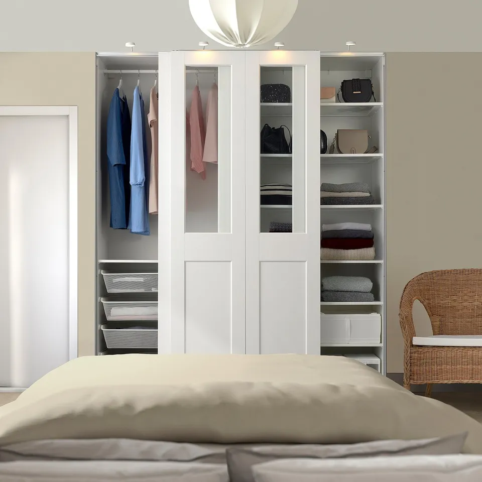 Large white PAX wardrobe with glass and covered panels, neatly organised with clothes and accessories.