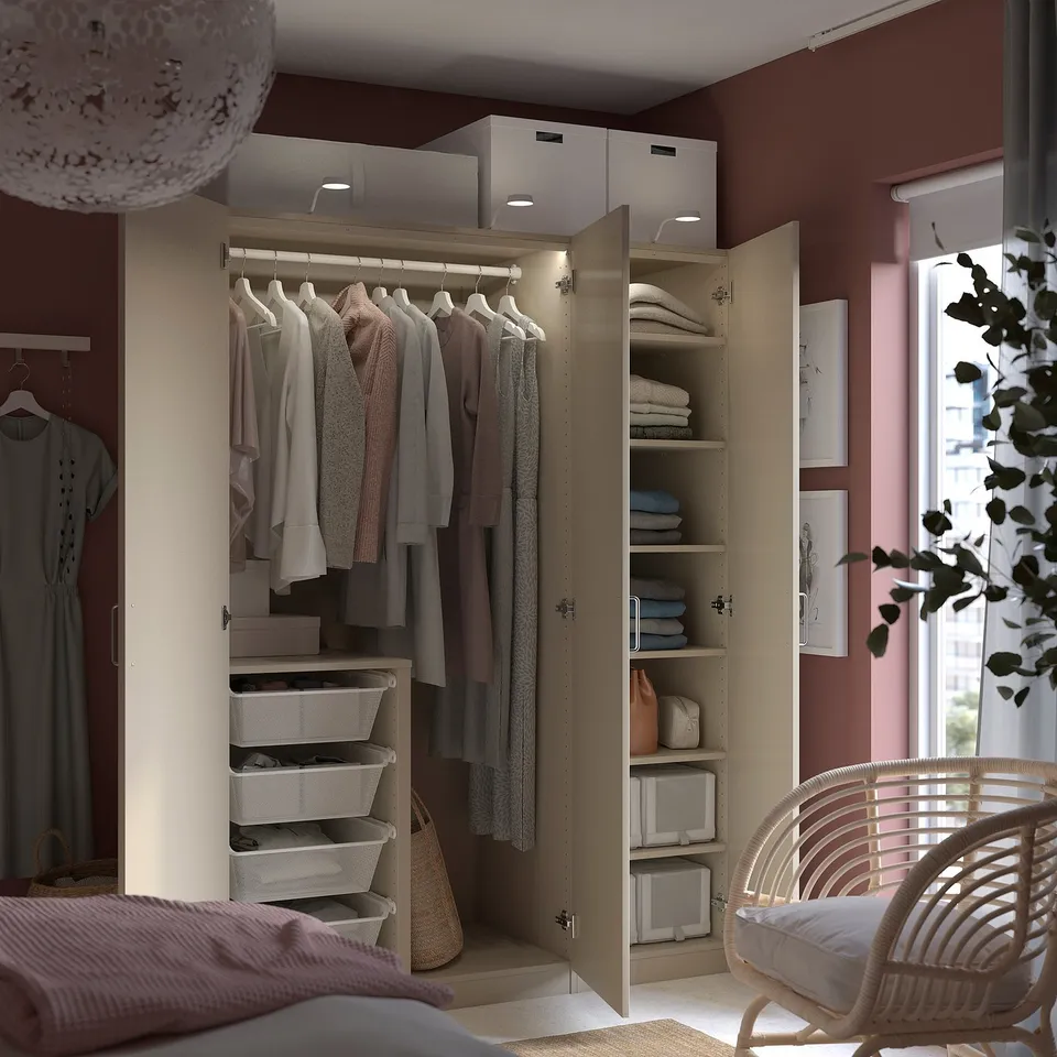Modern bedroom with PAX wardrobe, clothes, and wicker chair by a large window.
