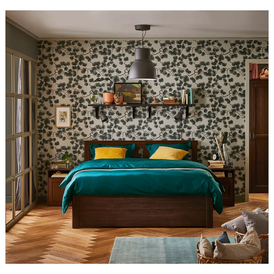 Bright bedroom with teal bedding, floral wallpaper, wooden floor, and hanging light.