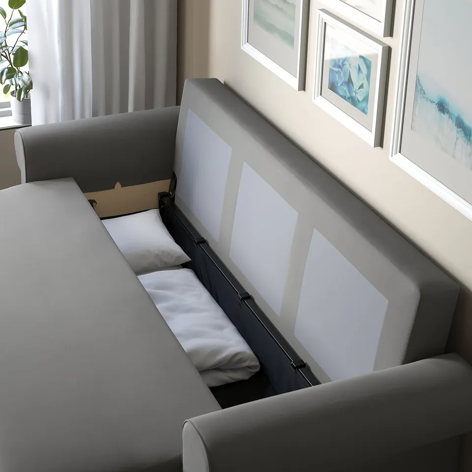 Grey sofa-bed with storage for bedding, featuring cushions and modern decor in living room.
