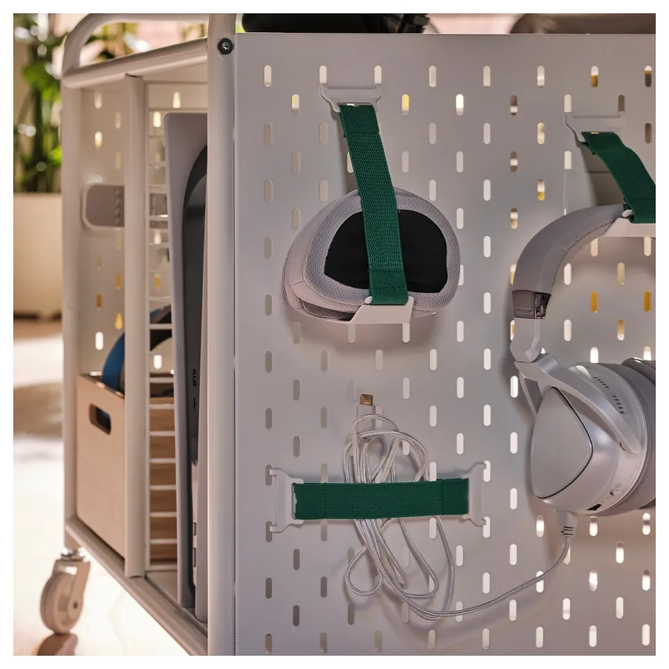 Modern gaming storage unit with pegboard, elastic straps holding headset and controllers, and side compartment for accessories.