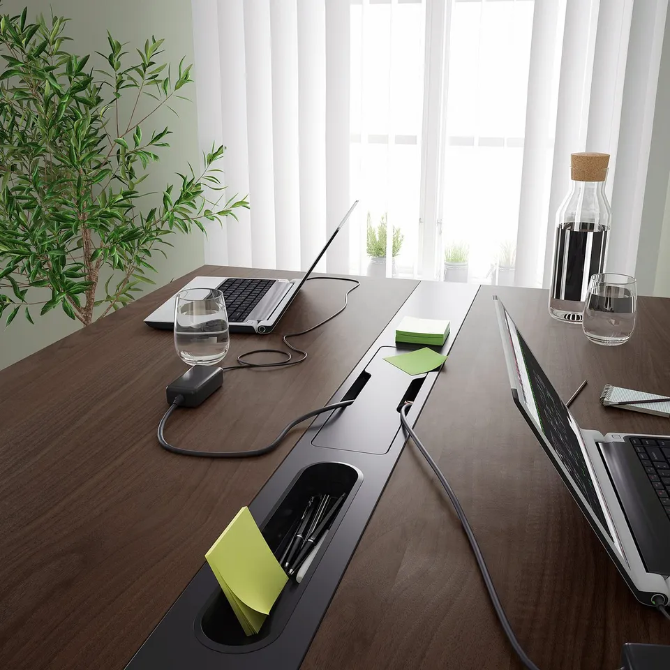 Conference table with built-in power outlets and cable management, suitable for both sitting and standing, perfect for professional meetings.