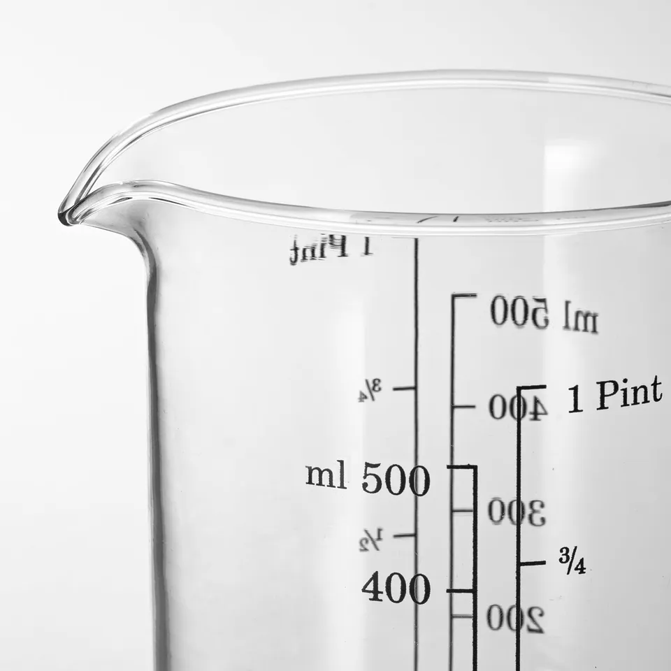 Clear glass measuring jug with black volume markings, spout for pouring.