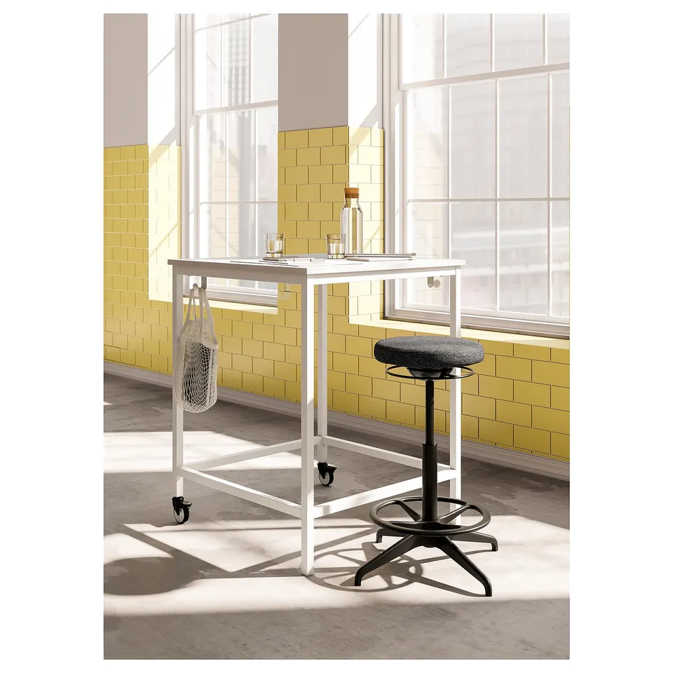 White LIDKULLEN stand-up desk with black adjustable stool, grey seat, by yellow-tiled windows.