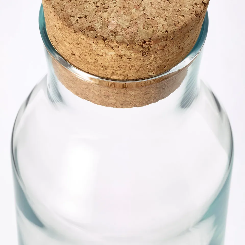 Clear glass carafe with cork stopper, simple and elegant design, suitable for cold drinks.