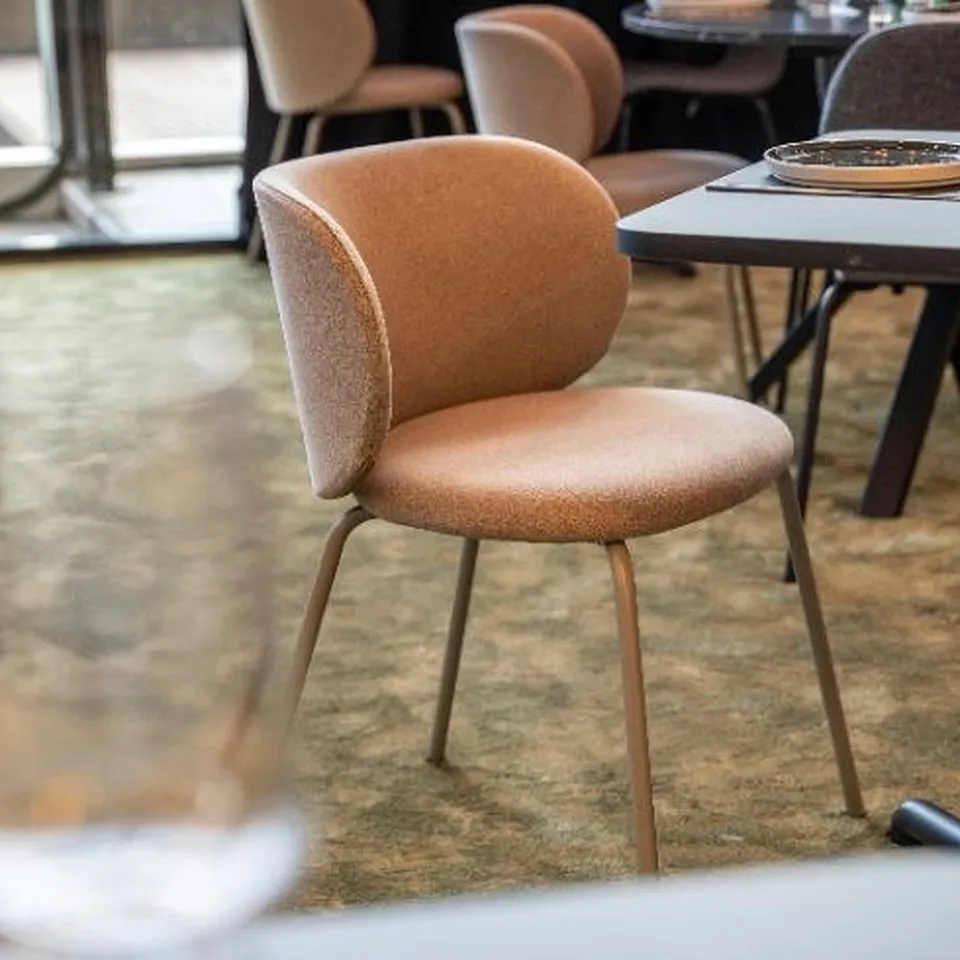 Brown upholstered chair with metal legs, designed for comfort during meals, shown in a dining area.
