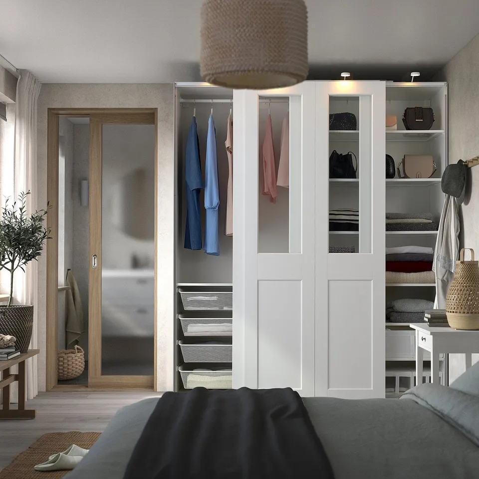 Modern bedroom with large white PAX wardrobe, glass panels, and hanging plant.