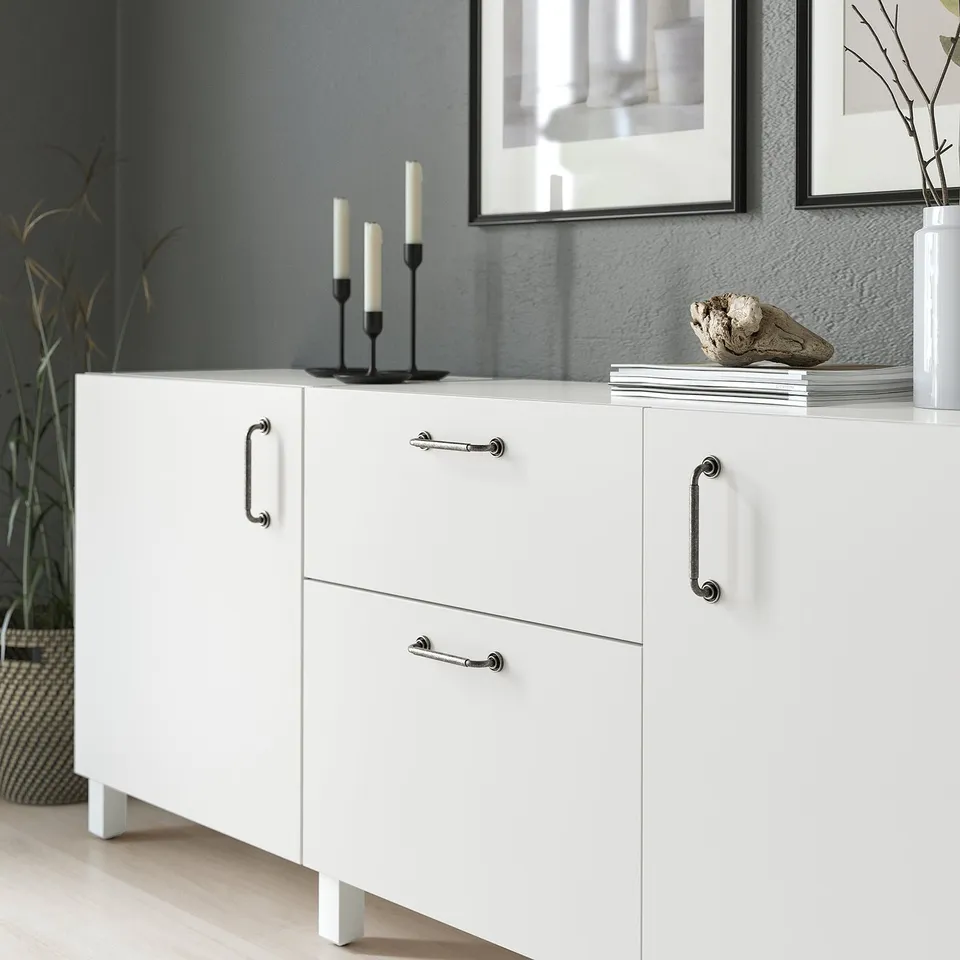 White cabinet with anthracite handles, displaying decor items.