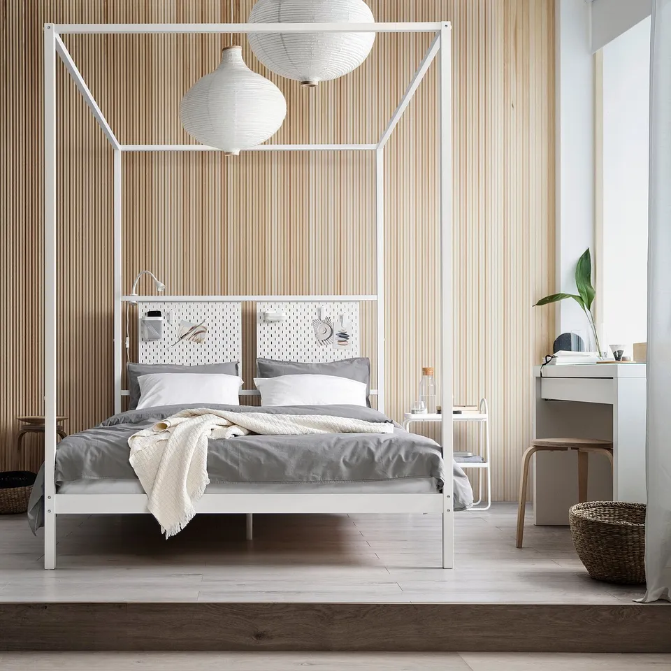 White four-poster bed with grey linens, wooden walls, and lanterns.