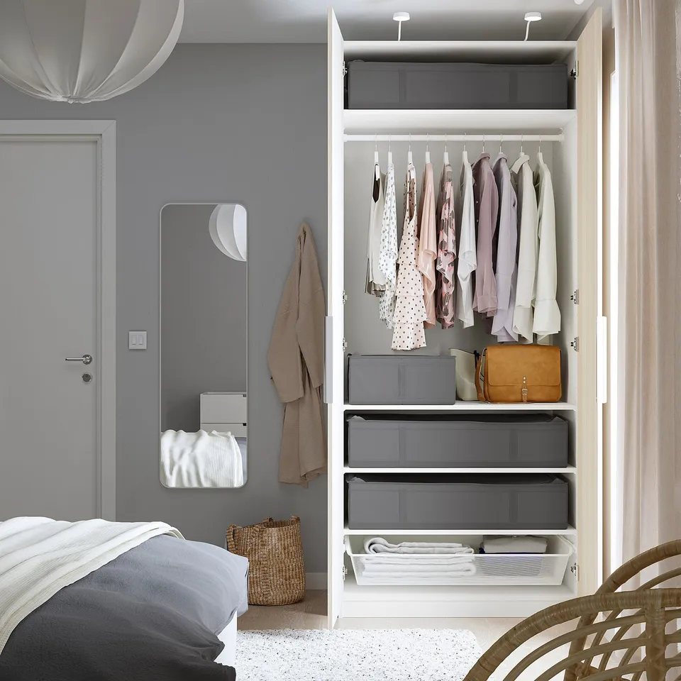 Bedroom with open closet showing clothes, storage boxes, and mirror, demonstrating SKUBB protective storage cases for seasonal clothes.