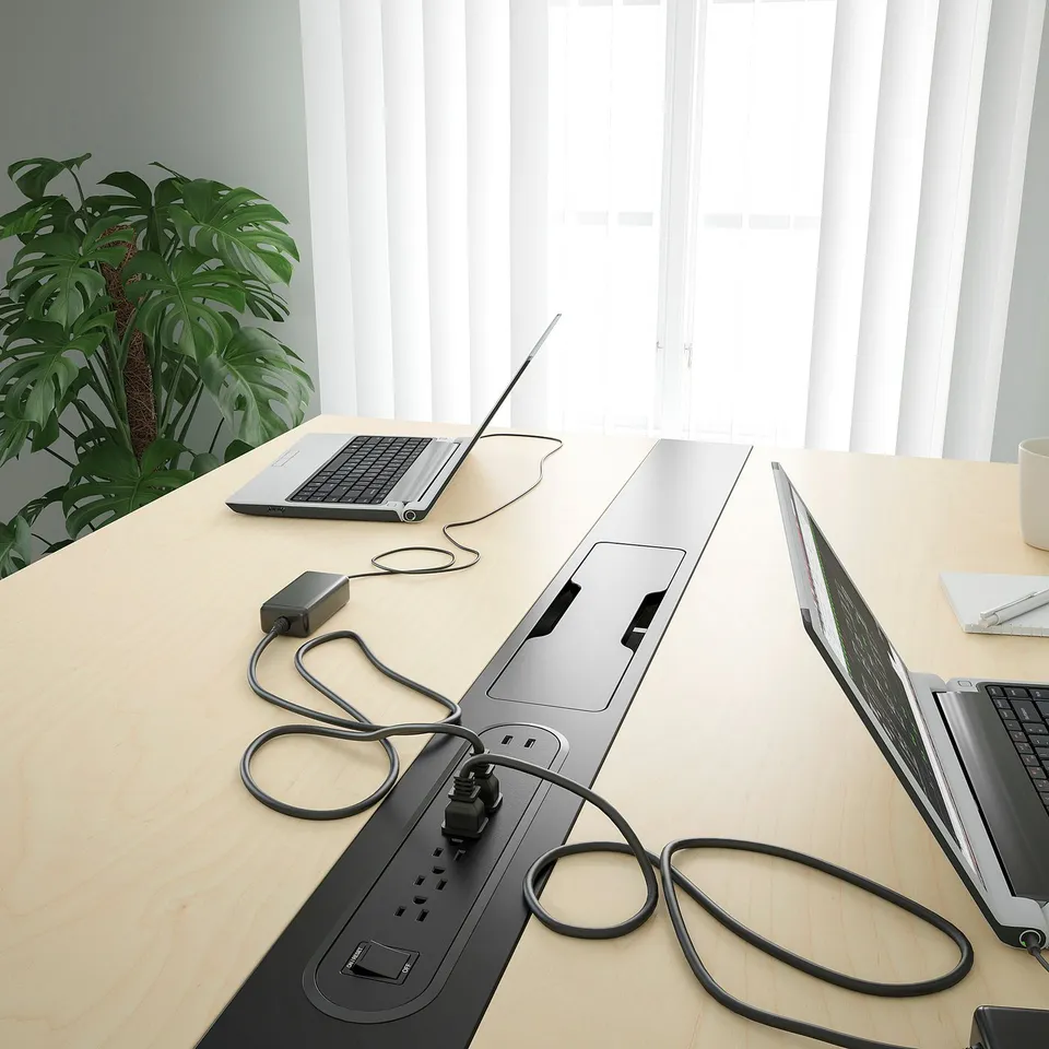 Conference table with integrated power strips, laptop connectors, and cable management.