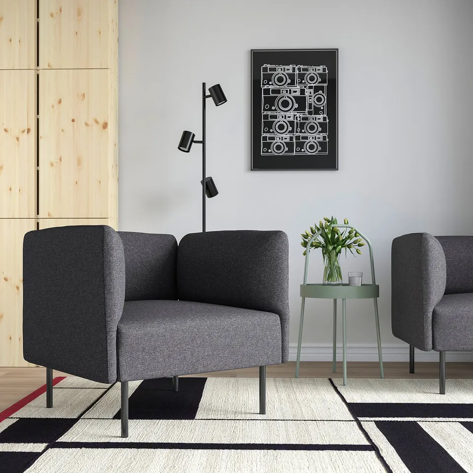 Modern living room with LILLEHEM armchairs, green side table, lamp, and camera poster. Minimalist decor with black & white rug and wooden panel.