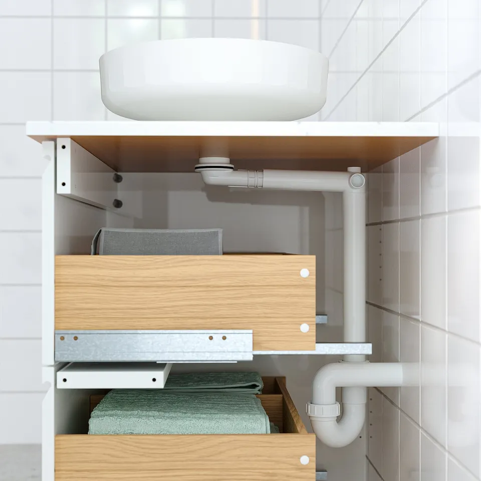 Modern bathroom setup with oak cabinet, circular countertop basin, and visible plumbing.
