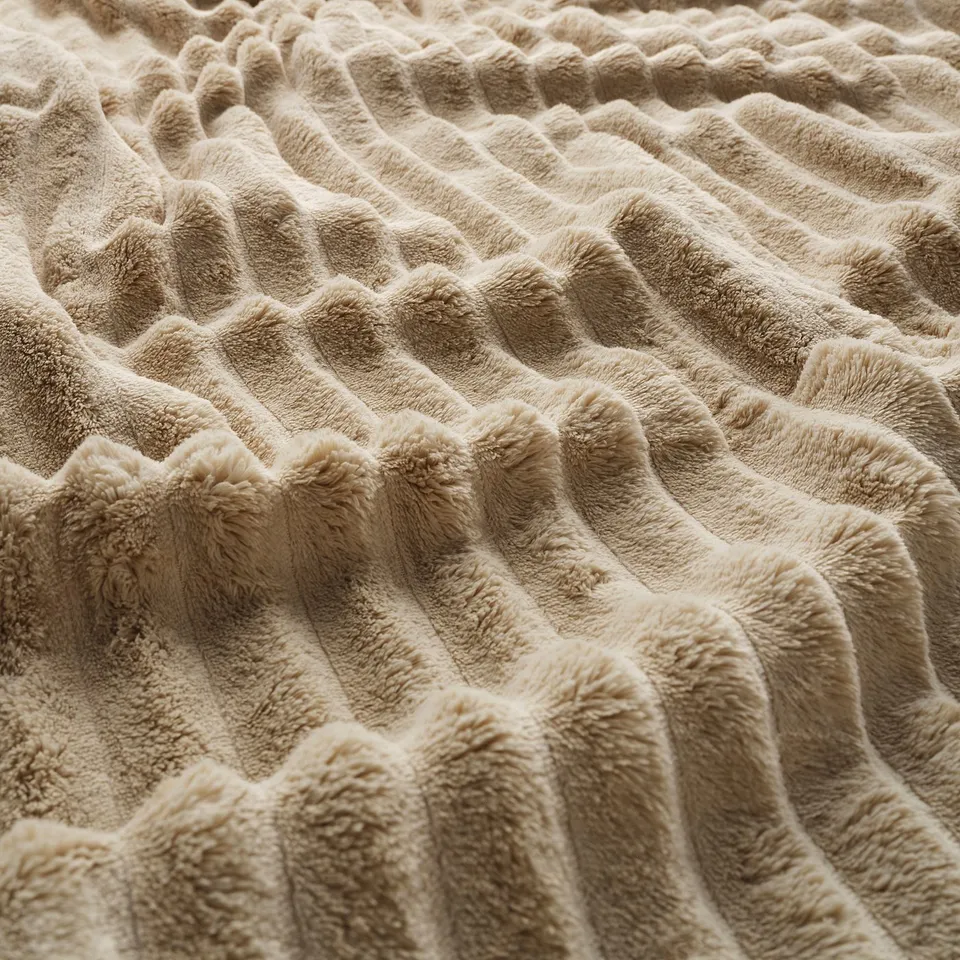A close-up of a plush, light-brown blanket with a soft, textured pattern, showcasing its cosy and inviting feel.