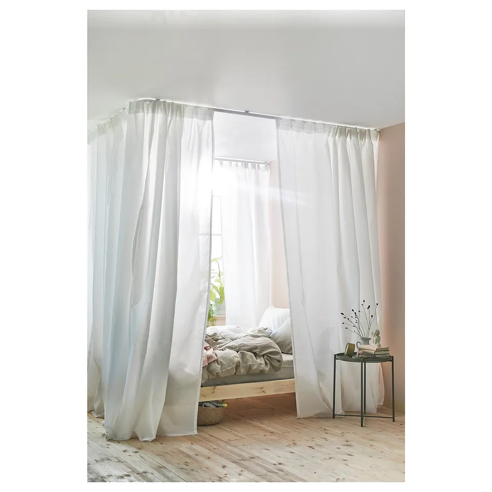 Bedroom with white VIDGA curtain rail system dividing space, creating cosy bed nook; sheer curtains.