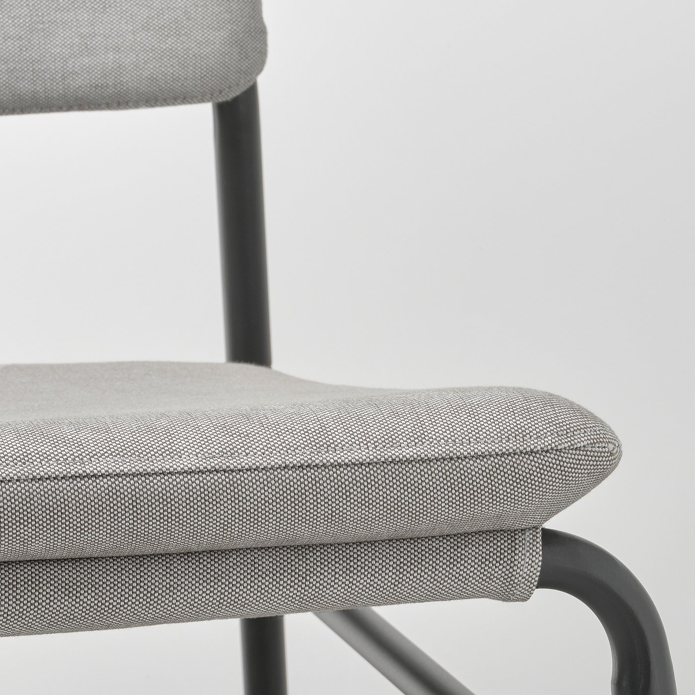 Close-up of a grey fabric-covered chair with black metal frame, showing quality stitching and design.