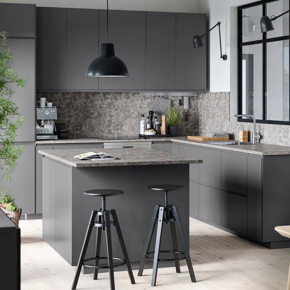 Modern grey kitchen with sleek cabinets, dark countertop, two bar stools, pendant light, and minimalist design.