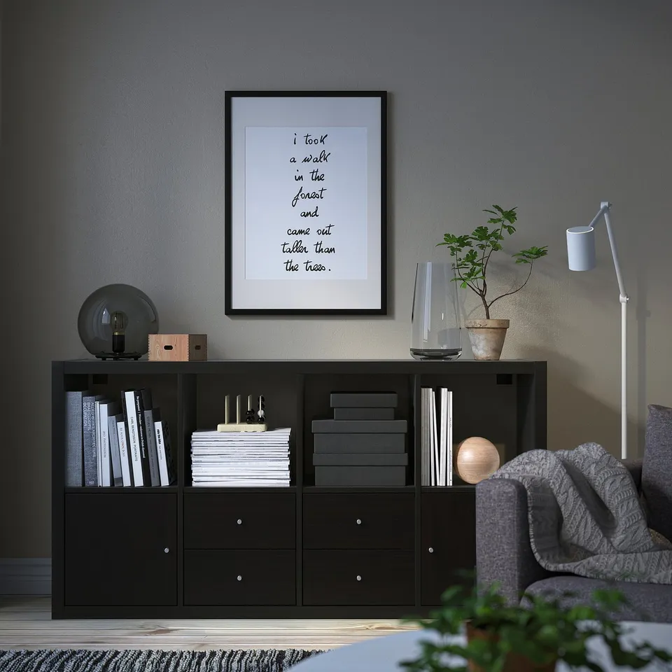 Black KALLAX sideboard with books, plant, and quote.