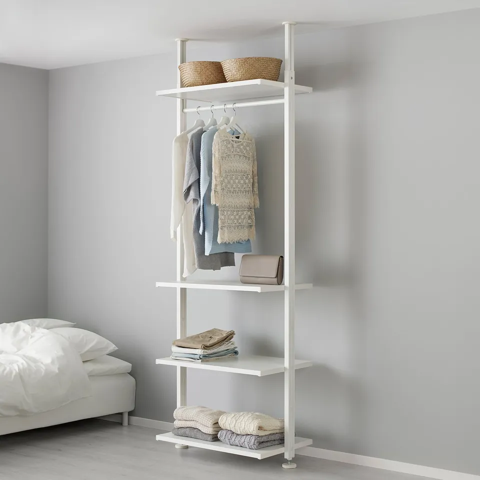 White ELVARLI storage unit with clothes, baskets, and folded items in bedroom.