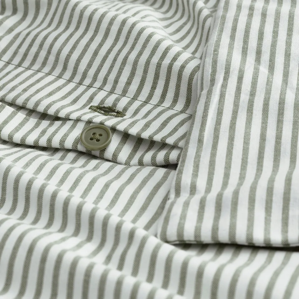 Close-up of a striped fabric shirt with a single button closure partially open.