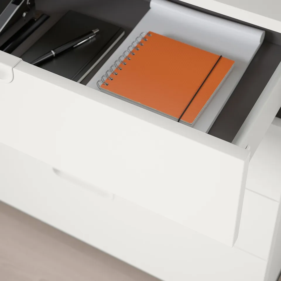 Drawer with orange notebook, pens, and folder.