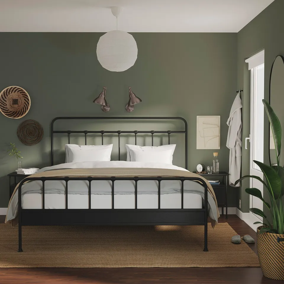 Modern bedroom: beige bed, green walls, black side table, white lamp.