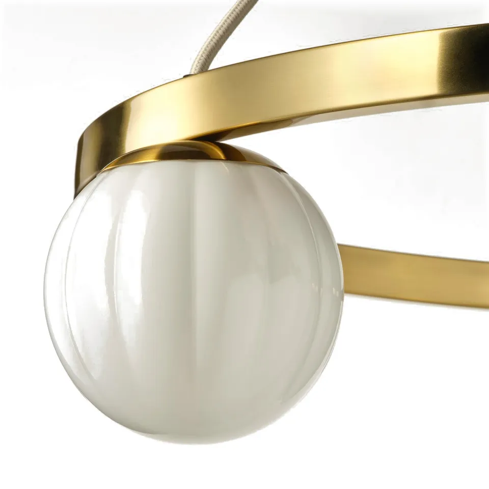 Close-up of a stylish pendant lamp featuring a gold-toned metal frame and a single, elegantly ribbed, white glass shade.