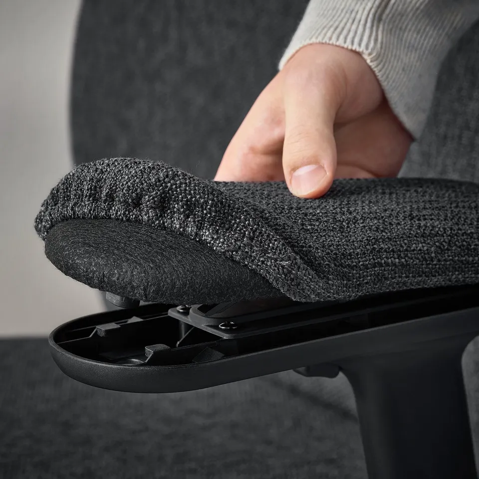 Hand adjusting ergonomic chairs armrest, demonstrating height and width adjustability for comfortable wrist support.